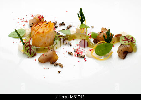 Une noix de Saint-Jacques saisie avec une croûte dorée repose sur une assiette blanche parmi du persil, de l'oseille à nervures rouges, des zestes de citron, des cubes blancs et des grains sombres gonflés. Une bande d'huile verte traverse l'assiette, saupoudrée de poudre rouge. Le plat provient de la carte du chef étoilé Michelin Thomas Figovc au "Libanon Lunch" (Lebanon lunch) à l'hôtel et restaurant Kronenschlösschen à Hattenheim, Eltville am Rhein, Hesse, Allemagne. Lors du 21e Festival Gourmet & Vin du Rheingau le 10 mars 2017, Figovc prépare un menu de quatre plats combinant la cuisine française avec des épices arabes. Depuis fin 2015, Figovc est directeur exécutif Banque D'Images