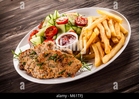 Côtelette de porc frit, des pommes de terre et légumes grillés sur table en bois Banque D'Images