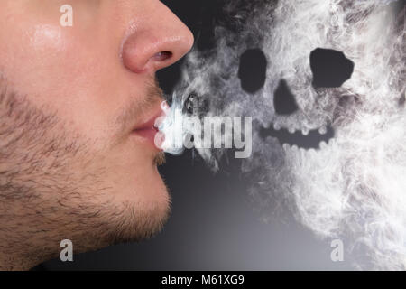 Close-up of a Man Smoking une forme de crâne formé Banque D'Images