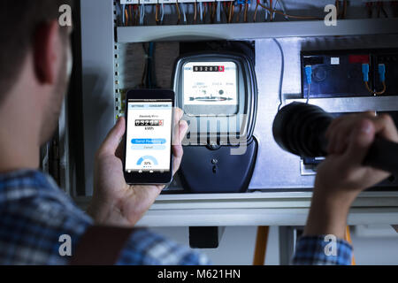 Close-up of a Man's Hand Holding Mobile Phone montrant compteur électrique Lampe de lecture et d'exploitation Banque D'Images