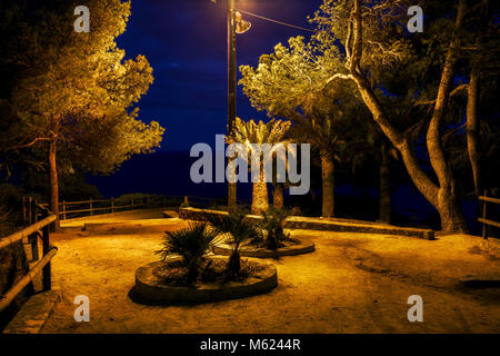 Carré sombre dans abandonded park par la mer à minuit illuminé par feu simple, Costa Brava à Lloret de Mar, Catalogne, Espagne Banque D'Images