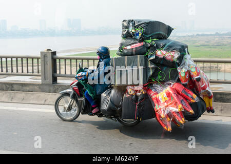 Une personne monte un scooter avec une très lourde charge de marchandises, généralement vu au Vietnam. Banque D'Images