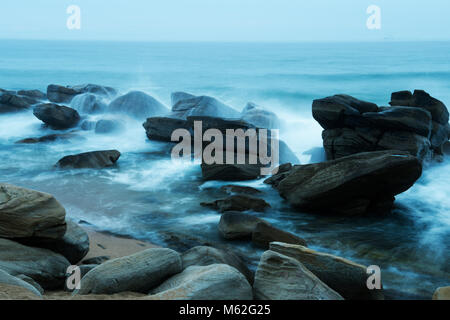 Durban, le KwaZulu-Natal, Afrique du Sud, flou, close-up l'eau de mer circulant sur les roches humides lisses en zone intertidale, plage d'Umhlanga Rocks, paysage Banque D'Images