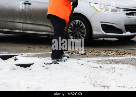 Le travailleur nettoie les voies de chemin de fer de la neige avec une pelle à la place des passages à niveau de l'automobile. Banque D'Images