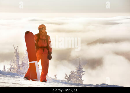 Snowboard planche à neige avec l'homme se tient en montagne contre ciel nuageux. Ski ou Snowboard concept avec place pour le texte Banque D'Images