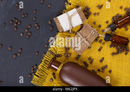 Cubèbe grains, savon, huile essentielle de cubèbe et sur une surface en bois. Vue d'en haut. Banque D'Images