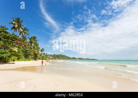La plage de Mirissa, Sri Lanka, Asie - DÉCEMBRE 2015 - Les touristes marcher sur le sable tout en appréciant la vue sur la magnifique plage de Mirissa Banque D'Images