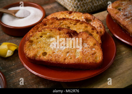 Une plaque en terre cuite avec quelques torrijas, dessert typique espagnol mangé dans le Carême et Pâques, et certains des ingrédients pour la préparer, tels que le sucre ou Banque D'Images