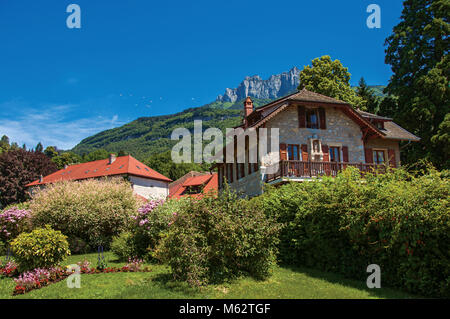 Vue sur les maisons et jardins fleuris avec ciel bleu paysage montagneux. Dans le charmant village de Talloires. Le sud-est de la France. Banque D'Images