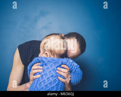 Une jeune mère avec un petit bébé en bleu Banque D'Images