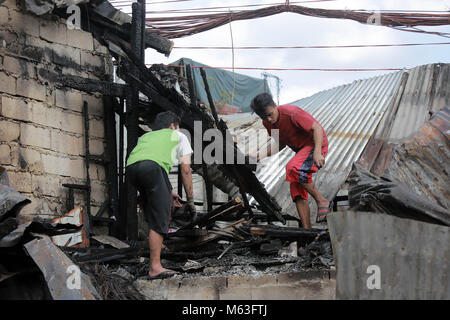 Quezon City, Philippines. 28 Février, 2018. Recherchez les résidents de collecte de matériaux à partir de leur holocauste accueil après un incendie dans un bidonville à Quezon City, Philippines, le 28 février 2018. Plus de 100 chantiers ont été rasées dans le feu, laissant 350 familles sans abri. Credit : Rouelle Umali/Xinhua/Alamy Live News Banque D'Images
