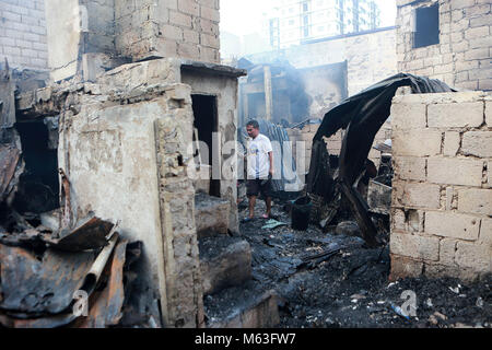 Quezon City, Philippines. 28 Février, 2018. Un résident recherche les matériaux réutilisables à partir de son domicile après un incendie dans un bidonville à Quezon City, Philippines, le 28 février 2018. Plus de 100 chantiers ont été rasées dans le feu, laissant 350 familles sans abri. Credit : Rouelle Umali/Xinhua/Alamy Live News Banque D'Images