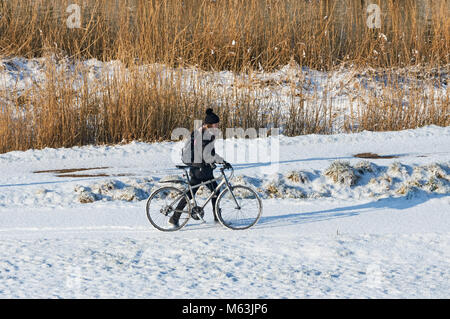 Jeune fille pousse son vélo dans la neige, Londres, Angleterre, Royaume-Uni, UK Banque D'Images