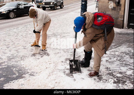 Edimbourg, Ecosse. 28 février 2018.. Météo France : averses de neige en raison de 'bête de l'Est' sur ville d'Edimbourg. Deux mens nettoyage du trottoir. Les attentes pour la journée sont plus averses de neige à cause de la météo fenomenon 'bête de l'Est'. Credit : Pep Masip/Alamy Live News Banque D'Images