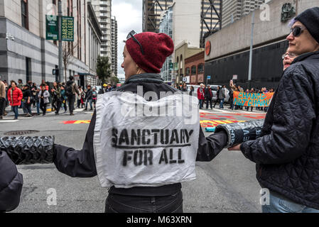 San Francisco, USA. 28 Février, 2018. Les manifestants forment une chaîne humaine à une intersection de San Francisco en signe de protestation. Environ trois cents manifestants se rassemblent à l'extérieur de San Francisco l'Immigration and Customs Enforcement (ICE) pour protester contre les récentes arrestations d'au moins 150 personnes dans les opérations menées au cours des derniers jours dans le Nord de la Californie. San Francisco reste une ville sanctuaire. Shelly Rivoli/Alamy Live News Banque D'Images