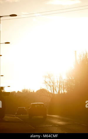 Voitures sont aveuglés par un faible soleil d'hiver le long de la route de conduite au Royaume-Uni Banque D'Images