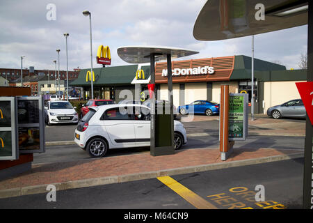 Jeune femme à l'alimentation de commande conducteur occupé à mcdonalds restaurant drive-in à l'heure du déjeuner en Irlande du Nord, Royaume-Uni Banque D'Images