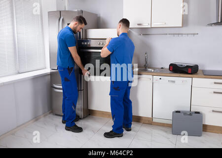 Deux jeunes hommes en uniforme bleu de four dans la cuisine de fixation Banque D'Images