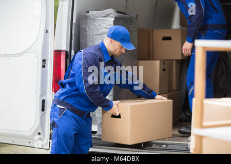 Vue latérale d'un jeune homme transportant des camions de boîte en carton Banque D'Images