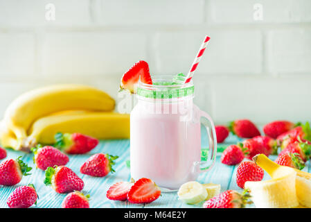 Les agriculteurs biologiques frais fraise et banane verser lait frappé à la bouteille dans un bocal en verre. Banque D'Images