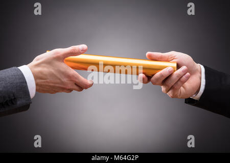 Close-up of a person's Hand Passing Baton d'affaires sur fond gris Banque D'Images