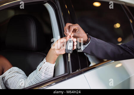 Situation des ventes en concession automobile, jeune couple obtient la clé de voiture neuve Banque D'Images