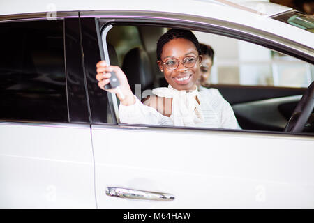 Femme africaine avec sa nouvelle voiture montrant les principaux Banque D'Images