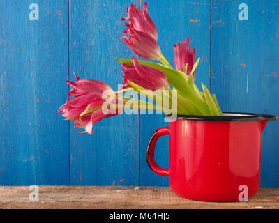 Beau bouquet de tulipes dans un vieux rouge tasse sur une table en bois Banque D'Images