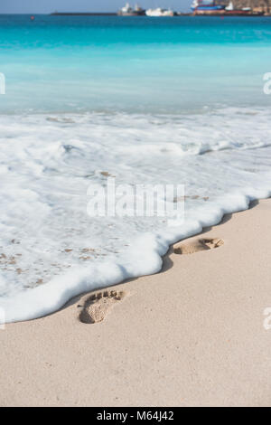 Les vagues de l'océan de toucher les empreintes de pieds sur la plage tropicale Banque D'Images