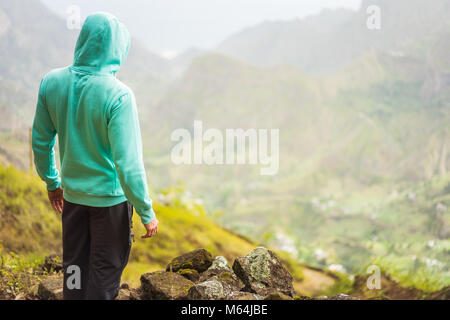 Tourist in hoodie en face du paysage rural avec des montagnes, sur le chemin de la vallée de Paul. L'île de Santo Antao, Cap Vert Banque D'Images