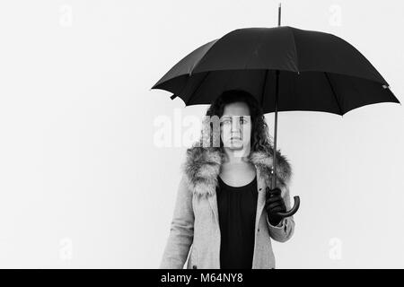 Curly belle femme élégante holding umbrella sur fond blanc à l'extérieur. Photo en noir et blanc. Banque D'Images