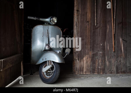 Trouver des vieux grange, Rusty de couleur bleu-gris scooter italien dans une cabane Banque D'Images