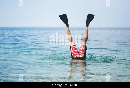 L'amusement à la mer. L'homme aux jambes avec palmes pour nager au-dessus de la surface de l'eau. Banque D'Images