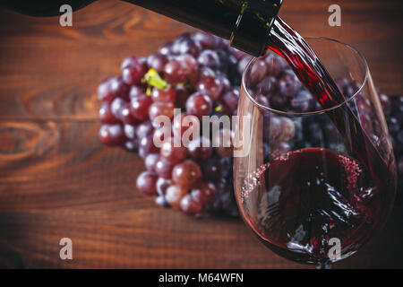 Bouteille et verre de vin rouge, les raisins et le liège sur fond de bois. Banque D'Images