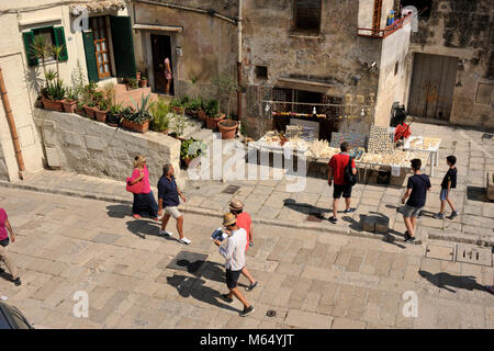 Italie, Basilicate, Matera, Sassi, Sasso Caveoso, rue pavée, touristes et boutique de souvenirs Banque D'Images