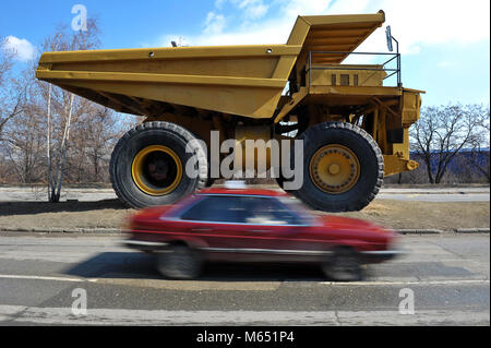 Petites voitures passant par big yellow mining truck Banque D'Images