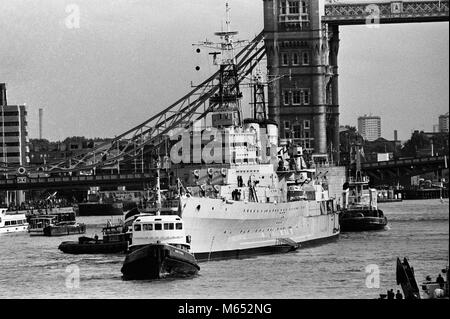 Avec des remorqueurs présents, le croiseur HMS Belfast à son arrivée dans le bassin de Londres. Les remorqueurs halé de Tilbury retour à son lieu d'amarrage à proximité de Tower Bridge, après des travaux importants de préserver sa coque. Banque D'Images