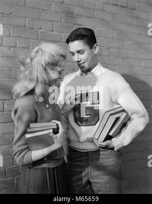 1950 TEENAGE COUPLE HOLDING BOOKS SMILING BOY LEANING AGAINST WALL LETTRE VARSITY SWEATER - BX018365 CAM001 CHOIX UNIVERSITÉS HARS 18-19 ANS FIERS DE SOUTENIR LA CROISSANCE DE LA CONNEXION DE L'ÉCOLE SECONDAIRE D'ENSEIGNEMENT SECONDAIRE ENSEIGNEMENT SUPÉRIEUR LES JEUNES ADULTES JEUNES ADULTES HOMME FEMME B&W NOIR ET BLANC à l'ANCIENNE Origine ethnique Caucasienne Banque D'Images