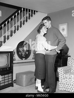 1950 HUGGING COUPLE DANCING IN LIVING ROOM - d3720 HAR001 AMITIÉ HARS LONG CÂLIN COPAIN CARING WOMAN WOMAN INDOORS FAIRE PLACE AU DIVERTISSEMENT NOSTALGIE VIVRE ENSEMBLE 13-15 ans 16-17 ans datant GIRLFRIEND STYLES SALON DES LOISIRS 18-19 ans Jeunes adolescents MODE CONNEXION RELATIONS AIME ALLER JUVÉNILES CONSTANTE B&W NOIR ET BLANC CHAUSSETTES BOBBY premier amour l'origine ethnique caucasienne old fashioned PENNY LOAFERS PERSONNES SLOW DANCE Banque D'Images