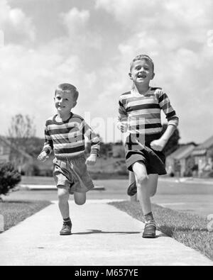 Années 50, DEUX FRÈRES GARÇONS SOURIANTS portant des shorts CHEMISES À RAYURES TOURNANT SUR UN TROTTOIR À LA CAMÉRA AU QUARTIER DE BANLIEUE - j1442 HAR001 HARS DE FORME PHYSIQUE FRÈRES NOSTALGIE TOGETHERNESS SUMMERTIME CONTACT OCULAIRE 7-9 ans 5-6 ans QUARTIER LIBERTÉ BONHEUR JOYEUX LOISIRS AVENTURE EXCITATION SHIRTS FRÈRE JOYEUX SOURIRES CROISSANCE ÉCHAPPER PANTALON COURT T-SHIRT juvéniles mâles TEE SHIRT B&W NOIR ET BLANC DE L'ORIGINE ETHNIQUE CAUCASIENNE LOOKING AT CAMERA Old Fashioned Banque D'Images