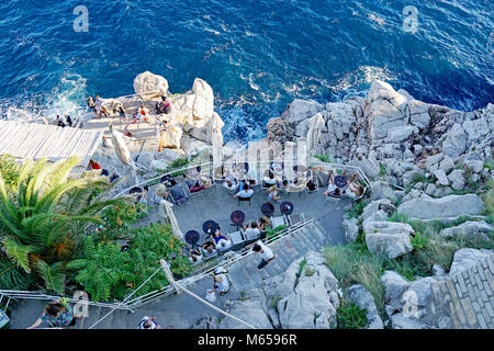 Les gens se détendre et avoir un verre dans un bar situé sur les roches par la mer, Dubrovnik, Dalmatie, Croatie Banque D'Images