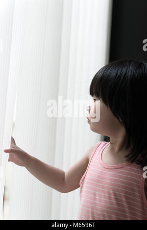 Triste petite fille à la fenêtre à Banque D'Images