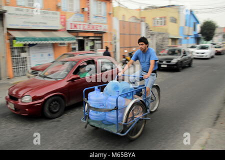Un homme sur une bicyclette transportant les boîtes de l'eau. Banque D'Images