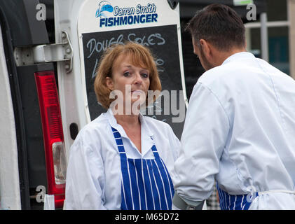 Femme en blouse blanche et un tablier à rayures d'un air narquois à la caméra regarde Banque D'Images