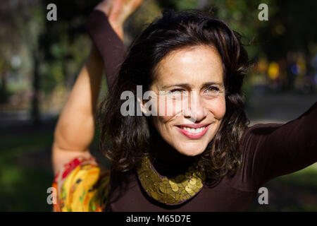 Gorgeous smiling lady pratique le yoga au parc. Femme d'âge moyen sur l'activité en plein air. Concept de vie sain Banque D'Images