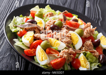 Salade niçoise de Thon, anchois, oeufs, tomates, haricots verts, olives et la laitue sur une assiette sur une table horizontale. Banque D'Images