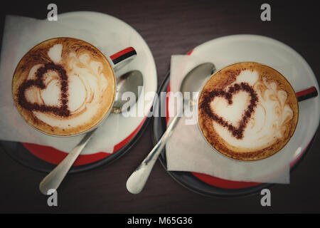 Deux tasses de café avec motif coeur dans une tasse blanche sur fond de bois. Concept d'amour. Banque D'Images