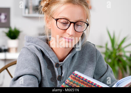 Jolie étudiante avec des livres à étudier à la maison. College girl doing homework at her desk Banque D'Images