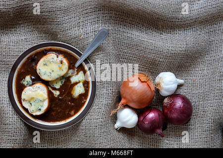 La soupe à l'oignon avec blue stilton fromage gruyère à l'ail, les échalotes et le français Echalion rouge et faire revenir les oignons dans un panier en osier sur une toile de jute backg Banque D'Images