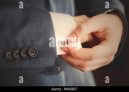 Groom mettant sur boutons de manchettes qu'il s'habille en tenue de cérémonie close up Banque D'Images